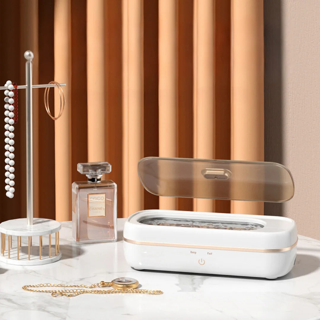 Shinevo ultrasonic cleaner on a dressing table with jewelry, perfume, and a watch nearby, ready for cleaning.