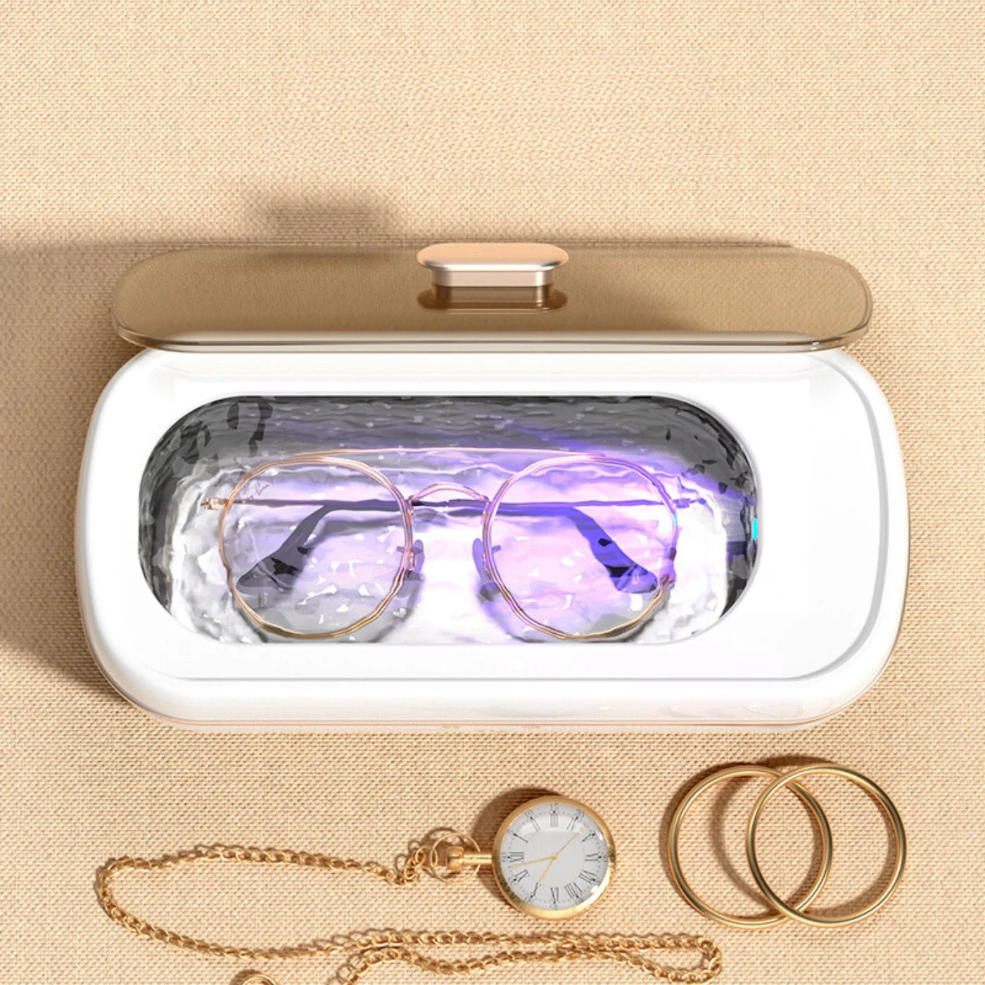 Shinevo ultrasonic cleaner on a dressing table cleaning eyeglasses with UV light, surrounded by gold jewelry and a pocket watch.